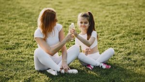 Caucasian mother and daughter in sportswear sharing a bonding moment outdoors.