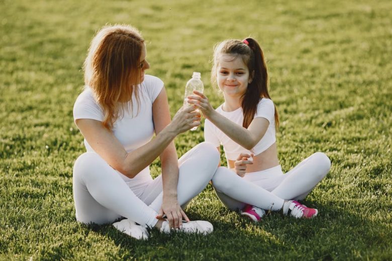 Caucasian mother and daughter in sportswear sharing a bonding moment outdoors.